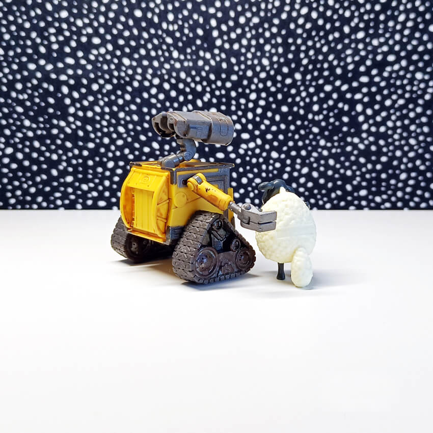 Wall-e le petit robot avec un mouton de dos devant un ciel étoilé